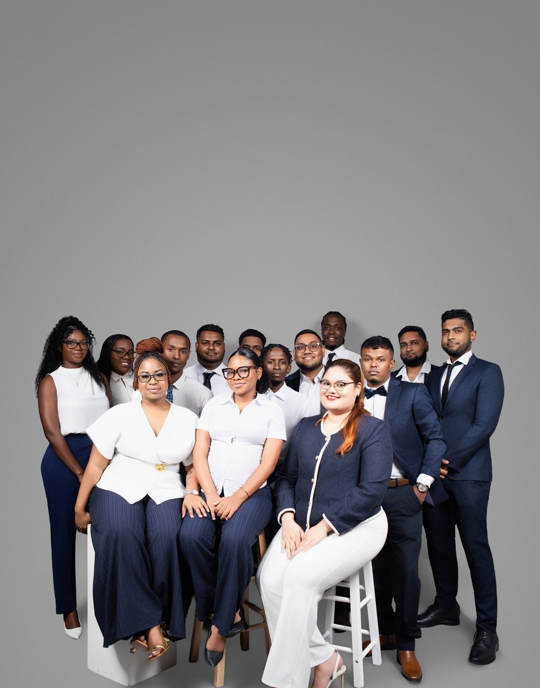 OSS staffing team of over a dozen employees posing together in a group studio portrait, Georgetown, Guyana