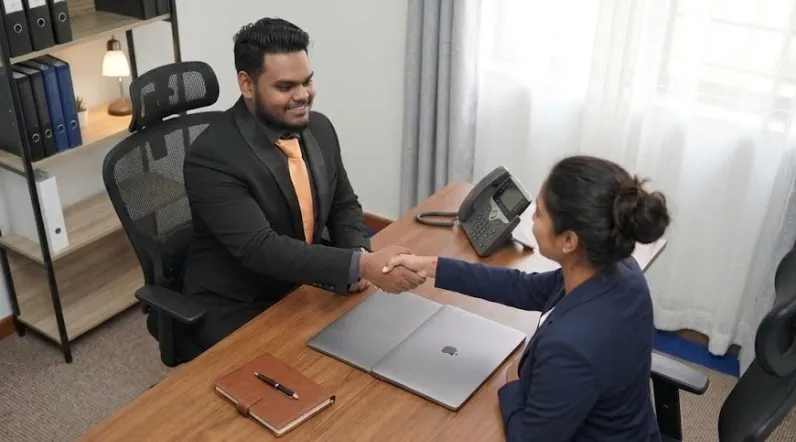 Khemraj Ramkissoon, Lead Service Coordinator at OSS, shaking hands with a client in the Georgetown, Guyana office