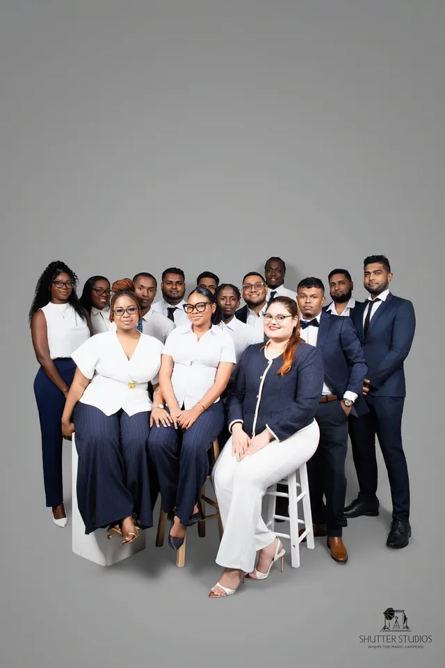 OSS staffing team of over a dozen employees posing together in a group studio portrait, Georgetown, Guyana
